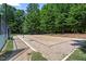 A sandy community volleyball court has a net and is framed by lush trees and greenery at 3021 Winding Waters Way, Raleigh, NC 27614