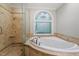 Main bathroom featuring a stand up shower and jetted tub with an ornate window at 3025 Bentwillow Dr, Fuquay Varina, NC 27526