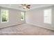Light-filled bedroom with three windows, neutral carpet, and a ceiling fan at 348 Danube Dr, Zebulon, NC 27597