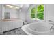 Bathroom with a soaking tub, double vanity, and a window overlooking the lush greenery outside at 3506 Arthur Minnis Rd, Hillsborough, NC 27278