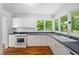 Bright kitchen featuring white cabinetry, stainless steel appliances, hardwood floors, and a large window with natural light at 3506 Arthur Minnis Rd, Hillsborough, NC 27278