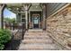 Inviting front porch with brick steps, stone accents, and black metal railings creates a cozy entry at 3601 Lily Orchard Way, Apex, NC 27539