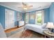 Bright blue bedroom features windows with natural light, hardwood floors, ceiling fan, and gray furniture at 429 Carolina Cir, Durham, NC 27707