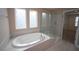 Bathroom with an oval soaking tub and glass shower enclosure, illuminated by natural light at 4416 Walker Hallow St, Raleigh, NC 27616