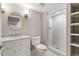 Bright bathroom with white tiled shower, marble vanity, oval mirror, and white shelving for a clean, modern look at 5509 Cliffwood Ct, Raleigh, NC 27609