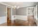 Bright dining room featuring hardwood floors, stylish chandelier, and classic wainscoting at 5509 Cliffwood Ct, Raleigh, NC 27609