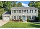 Charming two-story brick home with a manicured lawn, gray roof, black shutters, and a delightful blue front door at 5509 Cliffwood Ct, Raleigh, NC 27609
