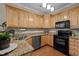 Well-lit kitchen features wood cabinets, granite countertops, and modern stainless steel appliances at 5515 South Roxboro # 32, Durham, NC 27713