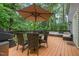 Outdoor deck has a table set, outdoor couch, umbrella, and is surrounded by peaceful nature views at 5900 Holly Dr, Raleigh, NC 27616