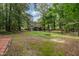 Expansive backyard surrounded by lush trees and greenery has a fire pit and cozy seating area at 5900 Holly Dr, Raleigh, NC 27616