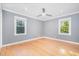 Neutral bedroom with hardwood floors, ceiling fan, bright lighting, and multiple windows at 5900 Holly Dr, Raleigh, NC 27616