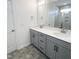 Bathroom with double sinks, grey cabinets, and a tiled shower at 67 Furley St., Homesite 117, Sanford, NC 27330