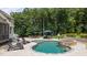 A luxury pool with a lounge area, outdoor dining, and stone-clad hot tub are surrounded by lush landscaping at 7410 Chouder Ln, Wake Forest, NC 27587