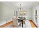 Elegant dining area featuring hardwood floors, a modern chandelier, and ample natural light for a warm ambiance at 7808 Sandy Bottom Way, Raleigh, NC 27613