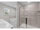 Well-lit bathroom featuring glass shower and a separate soaking tub beneath a window at 948 Consortium Dr, Raleigh, NC 27603