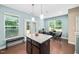 Bright dining area with large windows, modern light fixtures, and a granite island with seating at 102 Harvest Oaks Lane # 38, Durham, NC 27703