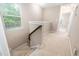 Carpeted staircase with a wooden handrail leading to the upper level, lit by a window at 102 Harvest Oaks Lane # 38, Durham, NC 27703
