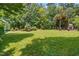 Expansive backyard featuring a lush green lawn and mature trees, leading to an outdoor fireplace area at 11124 Penderwood Ct, Raleigh, NC 27617
