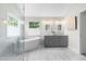 An updated bathroom with double vanities, sleek bathtub, and large window at 11124 Penderwood Ct, Raleigh, NC 27617
