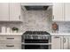 Close-up of kitchen featuring stainless steel oven, white cabinetry, white subway tile backsplash, and quartz countertops at 11124 Penderwood Ct, Raleigh, NC 27617