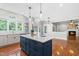 Bright kitchen featuring a navy blue island, white cabinets, stainless steel appliances, and hardwood floors at 11124 Penderwood Ct, Raleigh, NC 27617