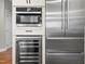 Modern kitchen with built-in microwave, stainless steel refrigerator, and wine cooler in white cabinetry at 11124 Penderwood Ct, Raleigh, NC 27617