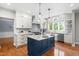 Bright kitchen featuring a navy blue island, white cabinets, stainless steel appliances, and hardwood floors at 11124 Penderwood Ct, Raleigh, NC 27617