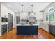 Bright kitchen featuring a navy blue island, white cabinets, stainless steel appliances, and hardwood floors at 11124 Penderwood Ct, Raleigh, NC 27617