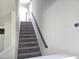 Carpeted staircase in neutral tones with bright white walls and handrail at 112 Wilbur Lake Dr, Fuquay Varina, NC 27526