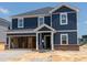 Two story home featuring a blue exterior, white trim and an attached garage awaiting finishing touches at 1233 Whitespire Way, Zebulon, NC 27597