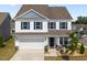 Charming two-story home featuring white siding, blue shutters, a two-car garage, and a welcoming front porch at 14 Shady Oaks Rd, Angier, NC 27501