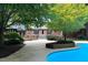 View of pool area with steps leading up to a brick patio on a tree-lined property at 14236 Wyndfield Cir, Raleigh, NC 27615