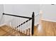 Staircase with hardwood floors and white railings leading to a hallway in a light and neutral color scheme at 14236 Wyndfield Cir, Raleigh, NC 27615