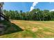 Wide shot of the backyard with a gentle slope and a lush, wooded backdrop at 164 E Spring Showers Trail Trl, Angier, NC 27501