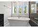 The bathroom features a luxurious soaking tub, designer fixtures, and a large window allowing natural light to fill the space at 164 E Spring Showers Trail Trl, Angier, NC 27501