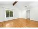 Bright living room boasts hardwood floors, large window, and vaulted ceiling with exposed wood beam at 18 Frances St, Chapel Hill, NC 27517