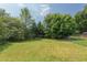 Large backyard with green grass, mature trees, and a chain-link fence creating a private outdoor space at 2014 Athens Ave, Durham, NC 27707