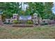 Stone entrance sign for Waterstone Estates, an Ashton Woods community, surrounded by lush greenery and colorful flowers at 205 Aurora Rd, Hillsborough, NC 27278