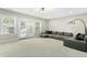 Spacious living room with carpet, featuring a large sectional sofa and bright natural light from the windows at 205 Aurora Rd, Hillsborough, NC 27278