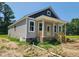 Inviting home exterior featuring gray siding, a covered porch, and manicured landscaping at 213 Maye St, Dunn, NC 28334