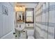 Compact bathroom featuring a toilet, sink, striped shower curtain, framed mirror, and window for natural light at 216 Northwood Cir, Durham, NC 27701
