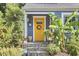 Close-up of the charming yellow front door with a wreath, blue siding, and stone steps at 216 Northwood Cir, Durham, NC 27701
