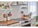 Close-up of a well-organized kitchen featuring a stove, butcher block countertop, and white subway tile backsplash at 216 Northwood Cir, Durham, NC 27701