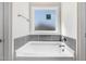 Clean, bright bathroom featuring a large tub with tile surround and a window for natural light at 222 Cherrybirch Ln, Zebulon, NC 27597