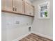 A tidy laundry room with overhead cabinets, wood-look flooring, and hookups for a washer and dryer at 222 Cherrybirch Ln, Zebulon, NC 27597