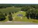 Aerial view of a charming country home with a large yard surrounded by green fields and mature trees at 224 Grameta Ln, Lillington, NC 27546