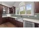 Modern kitchen features dark wood cabinets, stainless steel appliances, and a large window with a garden view at 228 Cloverdale Rd, Apex, NC 27523