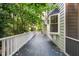 Long shaded back porch with a white railing overlooks a lush, tree-filled yard at 2504 W Club Blvd, Durham, NC 27705