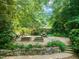 Serene backyard retreat featuring a stone retaining wall, mature trees, and outdoor seating at 2504 W Club Blvd, Durham, NC 27705