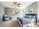 Comfortable primary bedroom with a ceiling fan, accent chair and three windows for natural light at 262 Salt Cedar Ln, Chapel Hill, NC 27516